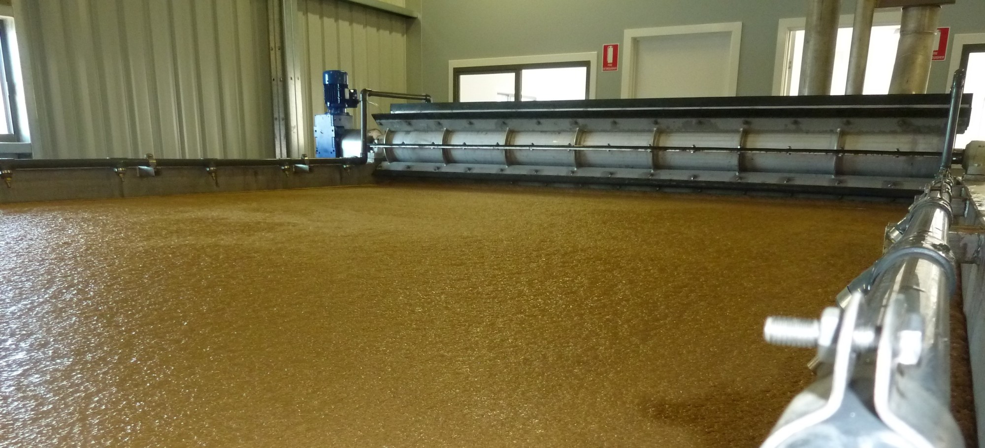 Low view across floated sludge to the rotary float skimmer and its drive motor at Coffs Harbour